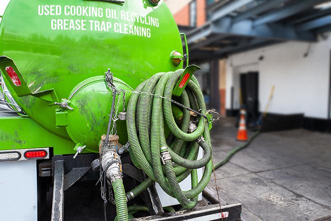 a grease trap pumping service in action at a commercial building in Acton